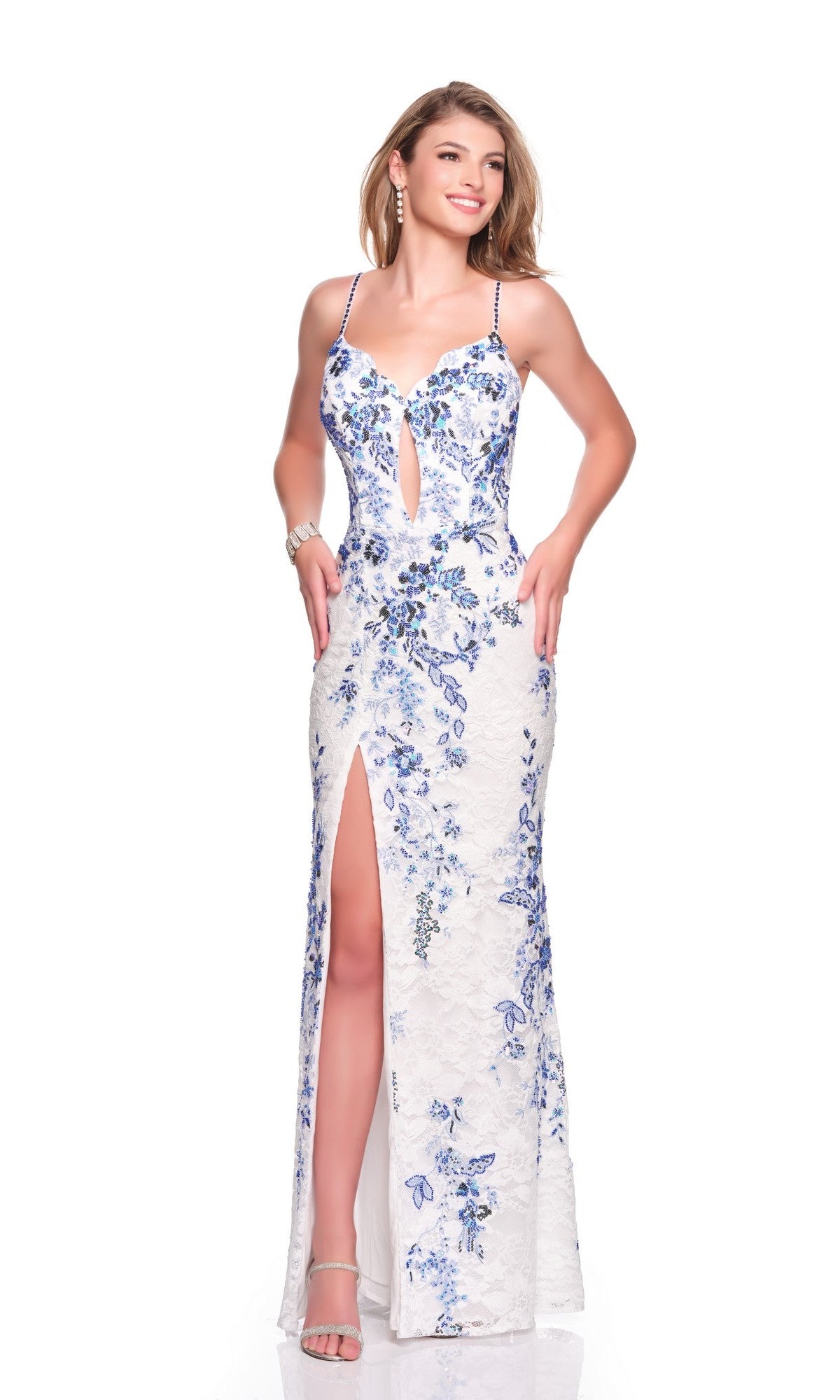 A woman in the Dave and Johnny 12877 long prom dress, featuring a blue fabric with white floral patterns, corset bodice, spaghetti straps, keyhole neckline, and front slit, stands against a white background.